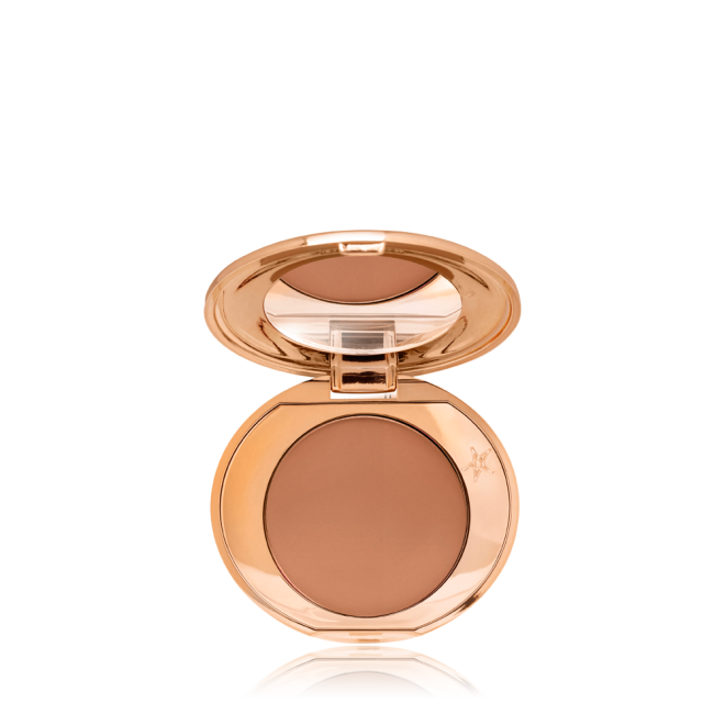 An open, mirrored-lid mini, pressed powder compact in a medium-brown shade, perfect for deep-tones. 