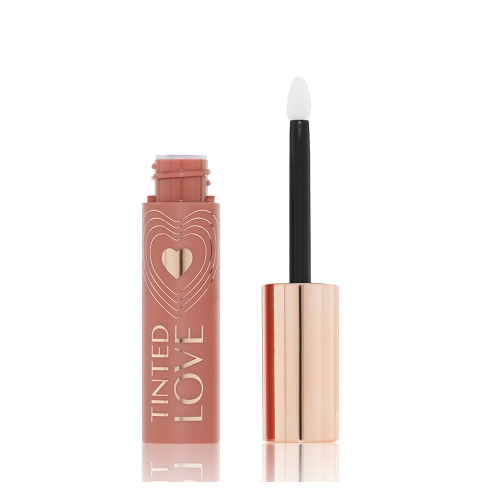 An open tube of lip and cheek tint in a sheer, tea rose colour with a gold-coloured lid and doe-foot applicator.