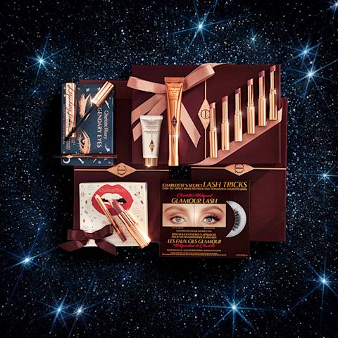 A collection of different makeup products that include lip kits, eye shadow palettes, lipsticks, highlighters and primers, and eye kits, all in front of a starry background. 