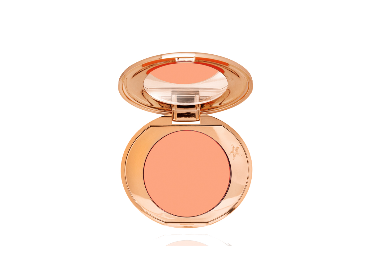 An open, mirrored-lid colour-correcting compact in a light peach shade. 