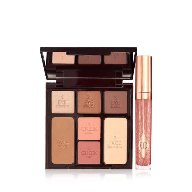 An open, mirrored-lid face palette with nude eyeshadows, nude pink and berry-pink blushes, light brown bronzer, and champagne highlighter with a nude pink lip gloss in a glass tube with a gold-coloured lid.