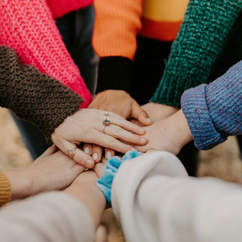 Women in a circle with their hands together on International Women's Day