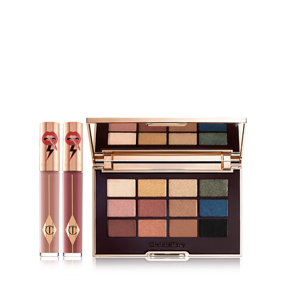 Two, closed liquid lipsticks in glass tubes in nude shades of brown and red with gold-coloured lids and an eyeshadow palette with matte and shimmery shades of brown, pink, green, gold, blue, and black.