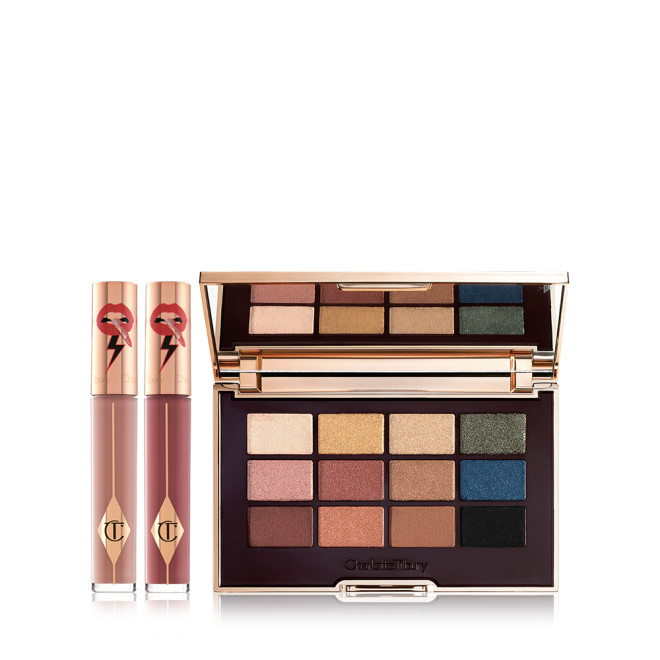 Two, closed liquid lipsticks in glass tubes in nude shades of brown and red with gold-coloured lids and an eyeshadow palette with matte and shimmery shades of brown, pink, green, gold, blue, and black.