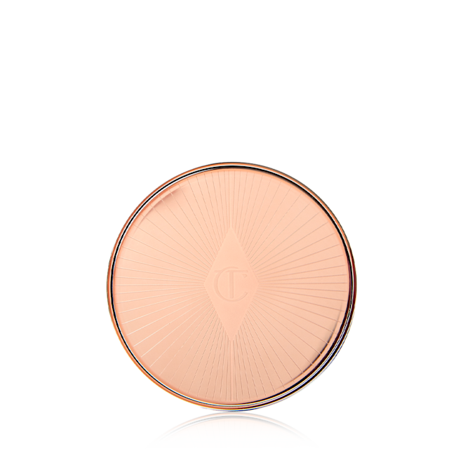 Lip and Cheek Glow closed A closed lip and cheek cream product compact with rose gold packaging and a starburst pattern on the lid.