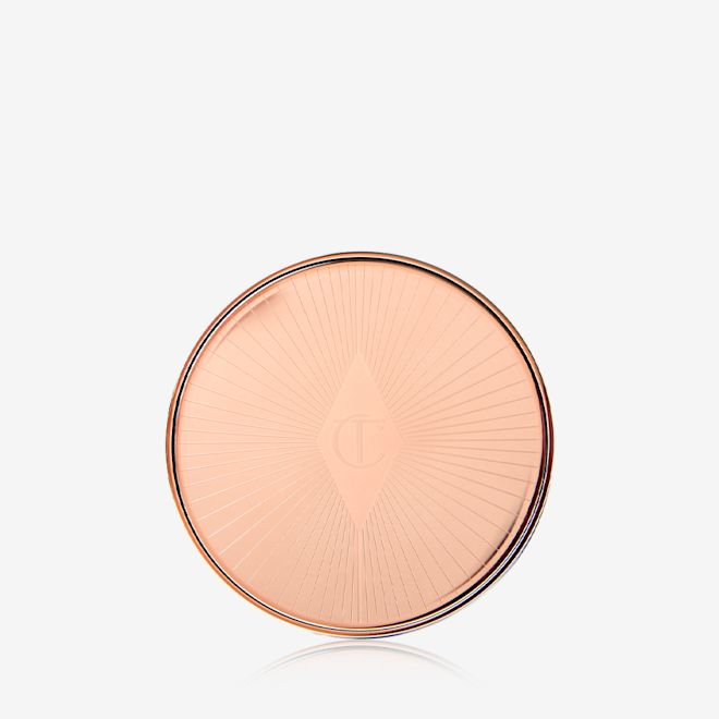 Lip and Cheek Glow closed A closed lip and cheek cream product compact with rose gold packaging and a starburst pattern on the lid.