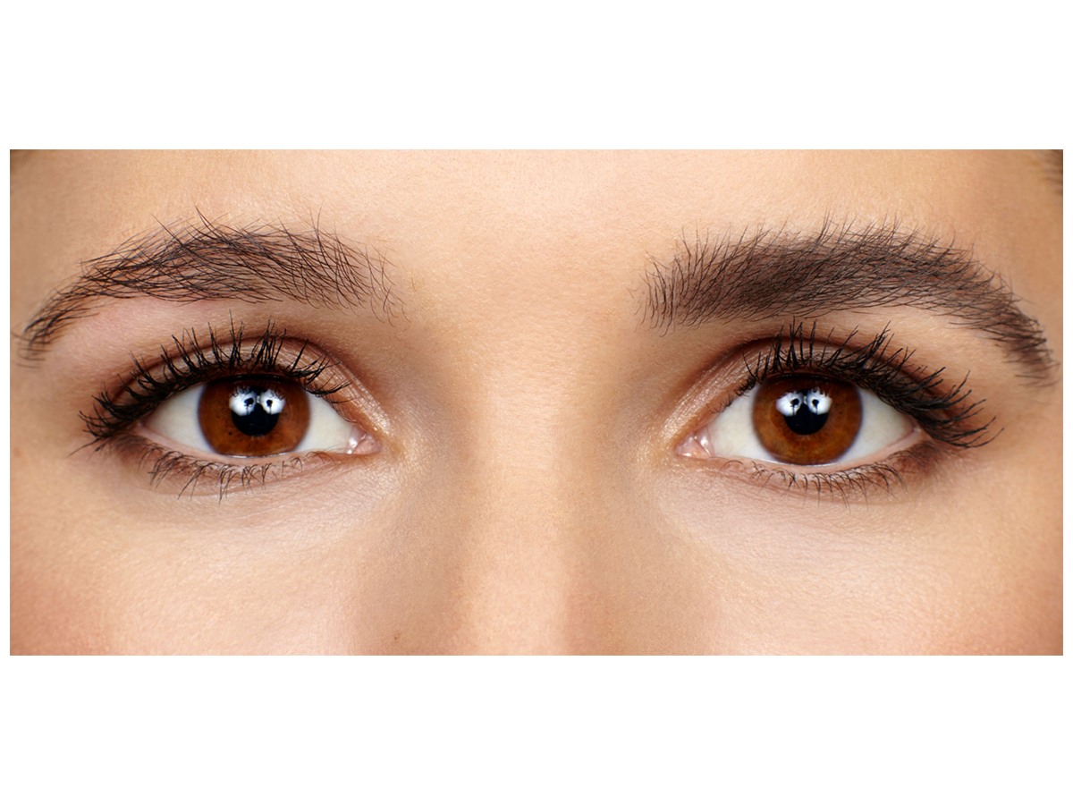 Eye close-up of a light-tone model with brown eyes with one eyebrow completely bare and the other filled and fluffed, looking lush and full.