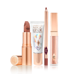 Lip gloss in a nude golden-brown shade in a glass tube with a gold-coloured lid, open nude peachy-brown lipstick in a gold-coloured tube, lip oil in a white-coloured tube with a reflective, geometrical pattern on the front, and a lip liner in a nude terracotta shade.