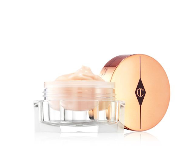 An open, light champagne-coloured eye cream in a glass pot with its rose-gold-coloured lid next to it. 