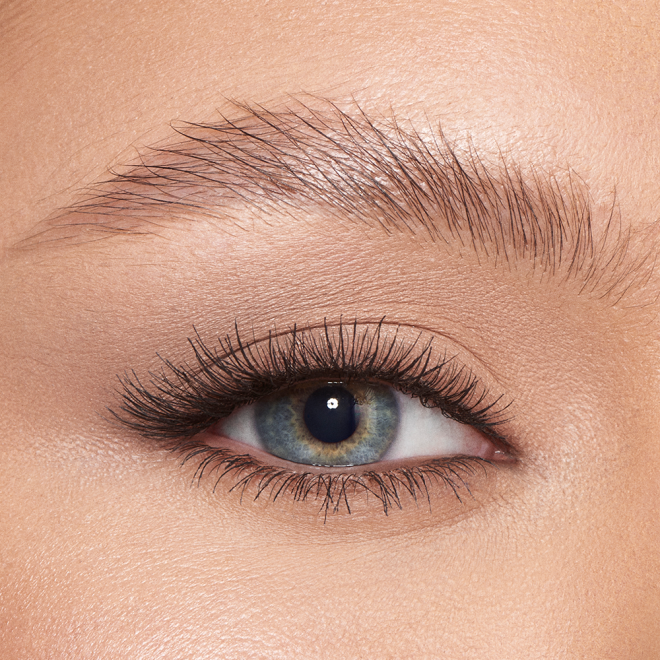 Single-eye close-up of a light-tone model with blue eyes with her eyebrows shaped and brushed with clear eyebrow gel.