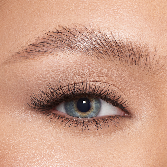 Brow Fix Clear Gel on light tone model close-up Single-eye close-up of a light-tone model with blue eyes with her eyebrows shaped and brushed with clear eyebrow gel.