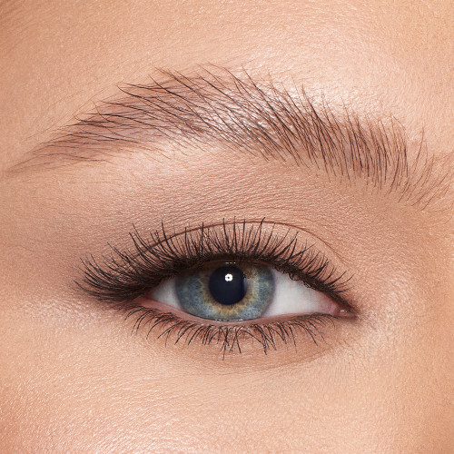 Single-eye close-up of a light-tone model with blue eyes with her eyebrows shaped and brushed with clear eyebrow gel.