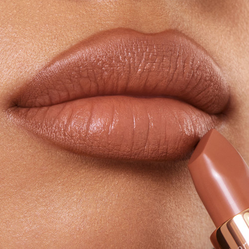 Lips close-up of a medium-tone model wearing a fresh, neutral nude peach lipstick with a matte finish.
