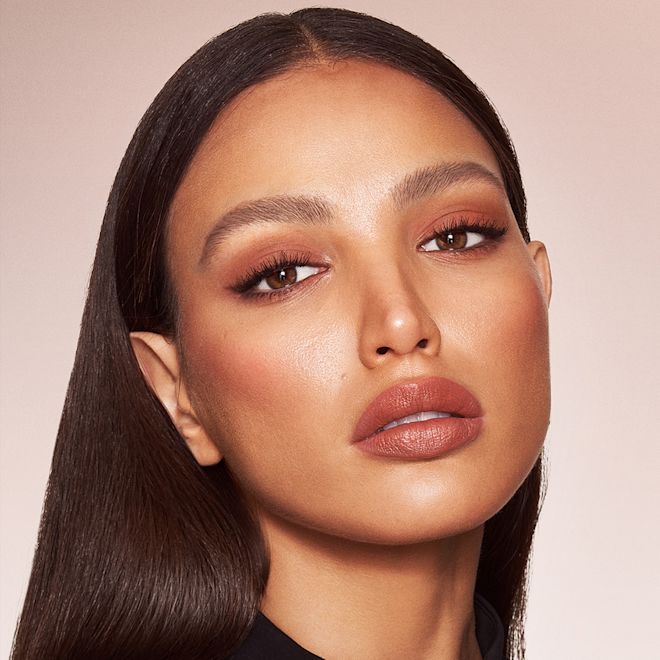 Quick & Easy Instant 5 Minute Super Chic Look on medium-tone brunette model Medium-tone brunette model with brown eyes wearing nude brown matte eye makeup with nude pink lip and cheek cream as blush and lipstick, and glowy opal-coloured highlighter.
