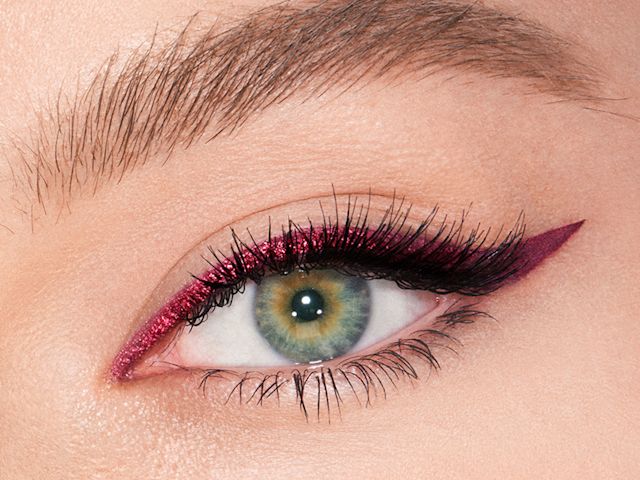 A fair-toned model with green eyes eye close-up of a sparkly maroon eyeliner with a soft wing in matte purple colour. 