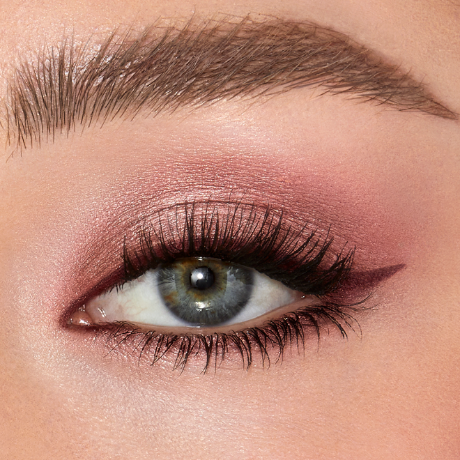 Single-eye close-up of a fair-tone model with blue eyes wearing shimmery rose gold cream eyeshadow.