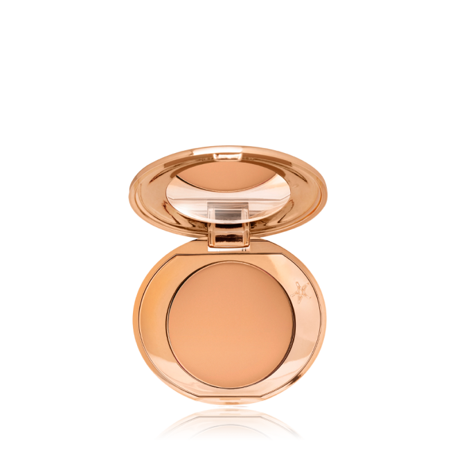 An open, mirrored-lid, mini, pressed powder compact in a sandy-brown shade. 