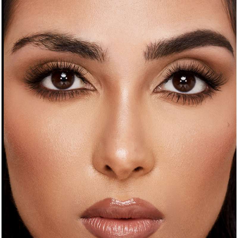 Close-up of a medium-tone model with brown eyes with bare brows on one side and thick, filled, and lined eyebrows on the other side after applying a dark-brown-coloured eyebrow pencil.