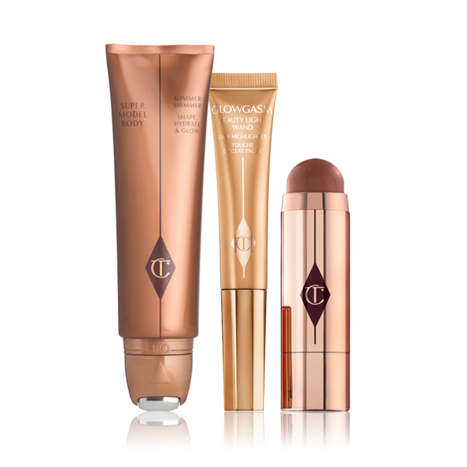 Body highlighter wand in a bronze tube, face highlighter wand in a honey-gold tube, a blush stick in a berry-red shade in gold packaging.