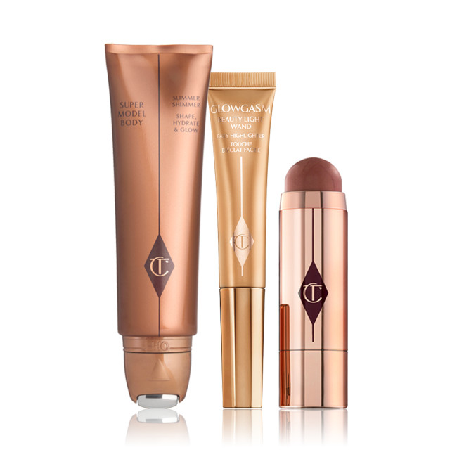 Body highlighter wand in a bronze tube, face highlighter wand in a honey-gold tube, a blush stick in a berry-red shade in gold packaging.