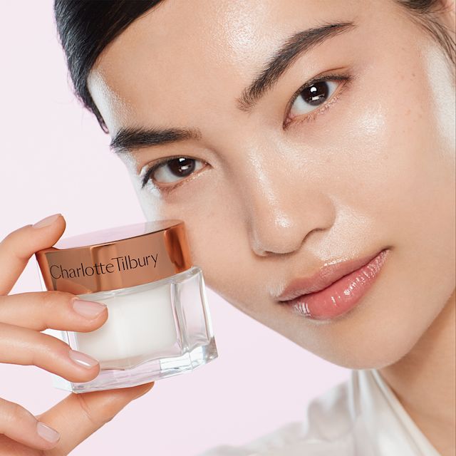 Chengxin applying Charlotte's Magic Cream to prep their skin for skin tint
