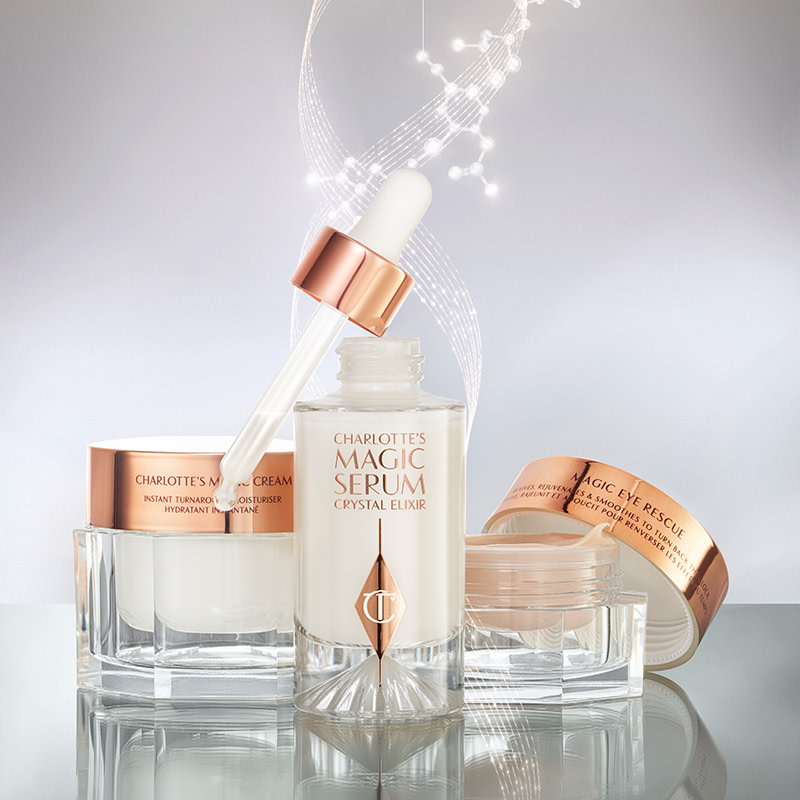 Luminous serum in a glass bottle with a dropper lid, pearly-white face cream in a glass jar with a gold-coloured lid, fawn-coloured eye cream in an open glass jar with a gold-coloured lid.