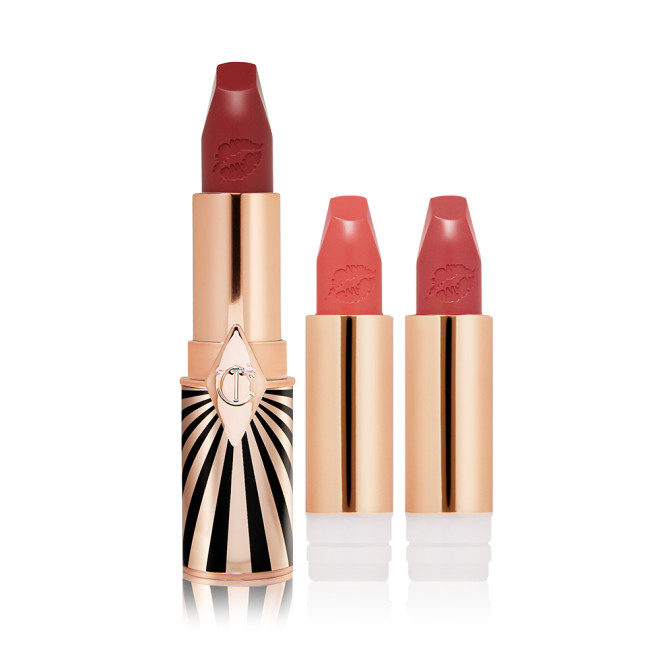 A maroon matte lipstick in a golden and red tube with a black and white print with two lipstick refills in muted red and brownish-peach,