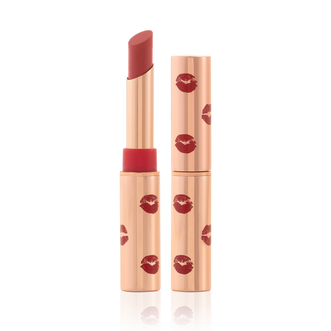 Two matte lipsticks, with and without lids, in gold-coloured tubes with kiss prints all over in dusty rose colour.