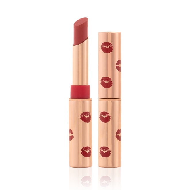 Two matte lipsticks, with and without lids, in gold-coloured tubes with kiss prints all over in dusty rose colour.