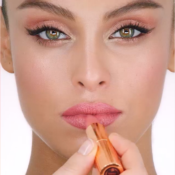 Le mannequin applique le rouge à lèvres KISSING en Bitch Perfect, un rouge à lèvres nude aux tons pêche avec une finition satinée.