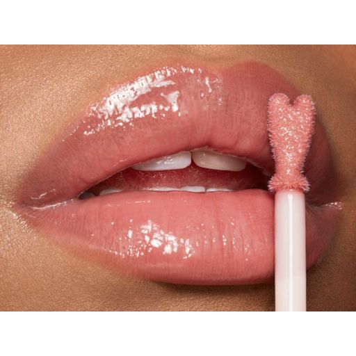 Lips close-up of a light-tone model applying sheer, nude pink lip gloss with a heart-shaped applicator. 