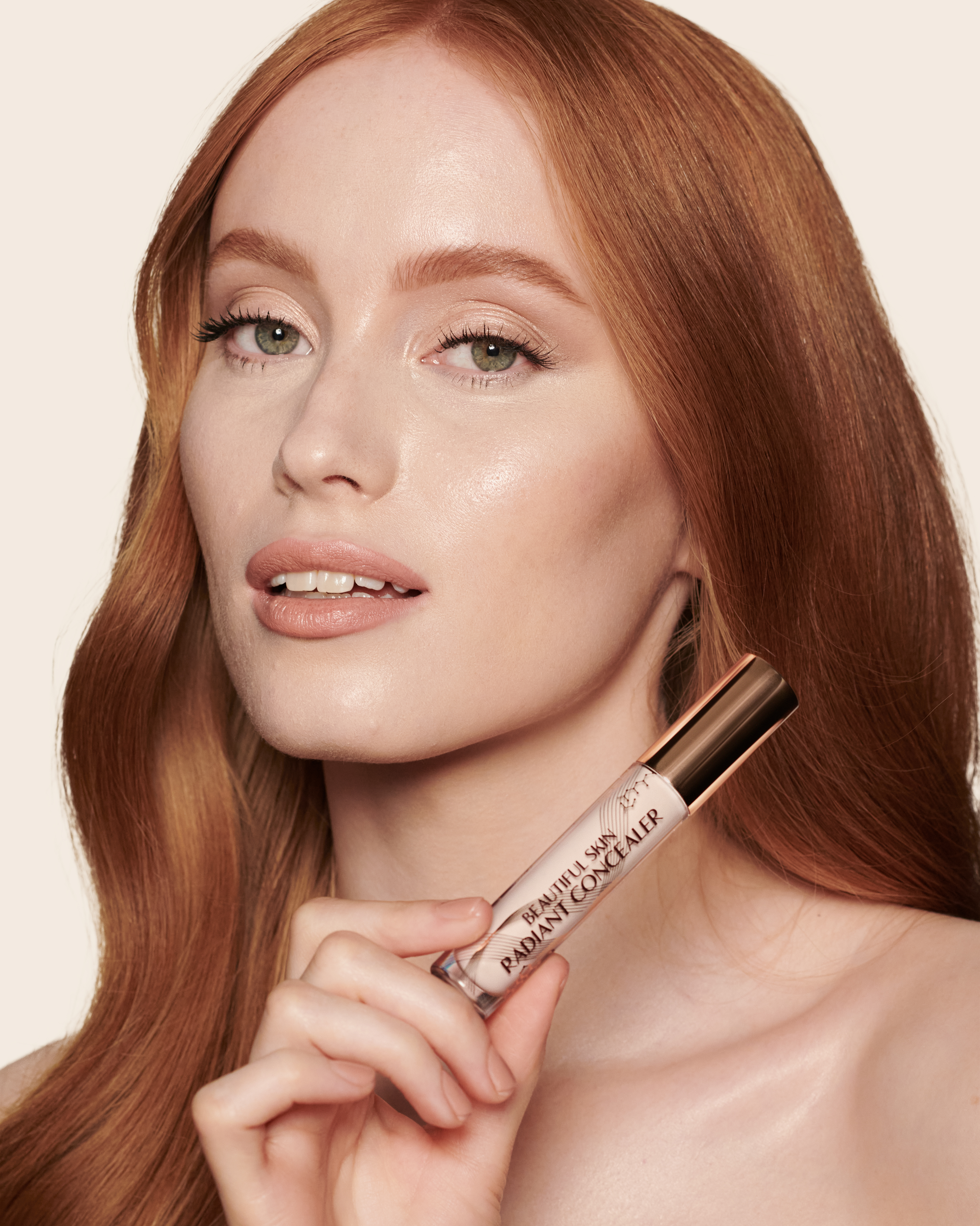 Fair-tone model with green eyes wearing a radiant, concealer that brightens, covers blemishes, and makes her skin look fresh along with nude lip gloss and subtle eye makeup.
