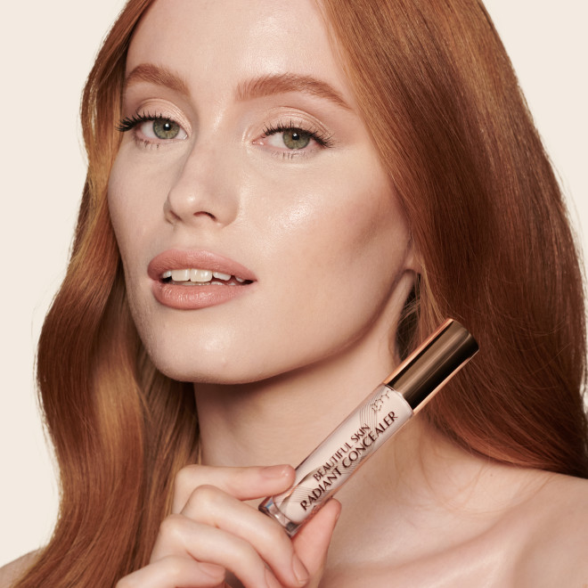 Fair-tone model with green eyes wearing a radiant, concealer that brightens, covers blemishes, and makes her skin look fresh along with nude lip gloss and subtle eye makeup.