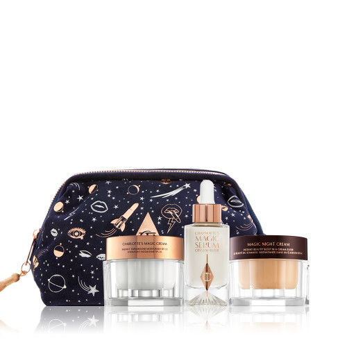 Pearly-white face cream and dark fawn-coloured night cream in glass jars with a luminous, ivory-coloured serum in a glass bottle with a dropper lid along with a avy blue makeup bag with the iconic CT logo in the middle and galaxy-theme illustrations printed all over the bag in white and gold colour. 