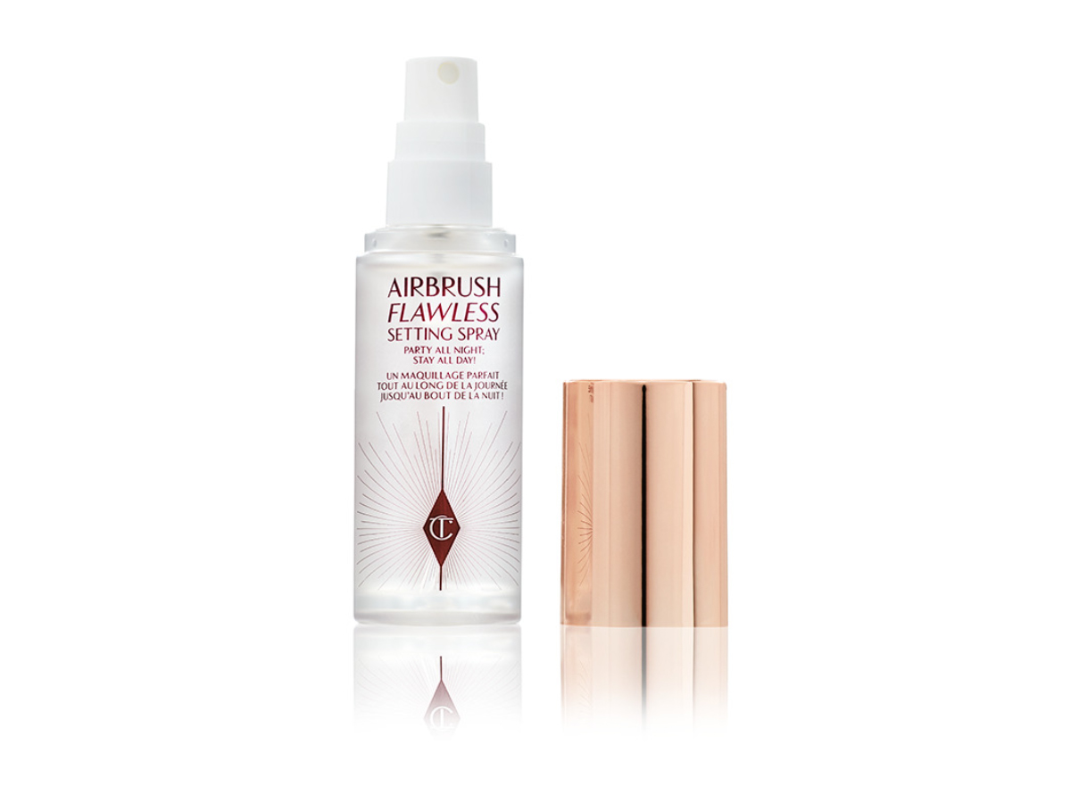 An open, travel-size setting spray in a clear bottle with a gold-coloured lid.