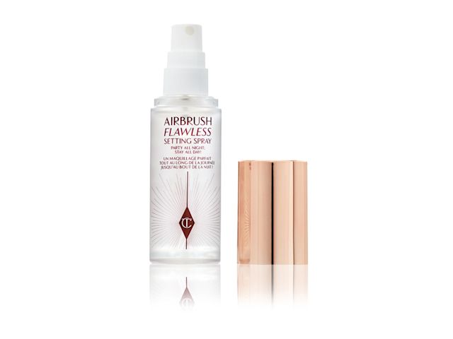 An open, travel-size setting spray in a clear bottle with a gold-coloured lid.