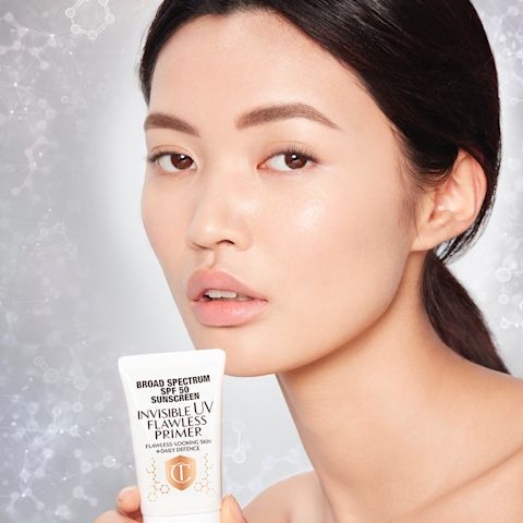 Fair-tone brunette model with brown eyes and glowy, smooth skin wearing a primer that makes her skin look flawless and glass-like. 