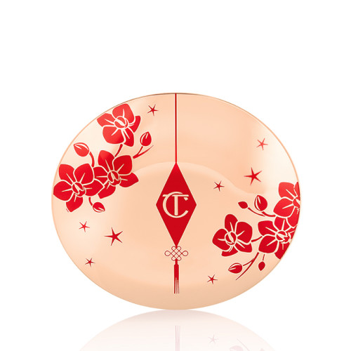 A closed powder compact with gold-coloured packaging and the CT logo printed on the lid in red and gold colour along with red cherry blossoms on the lid for the Lunar New Year.