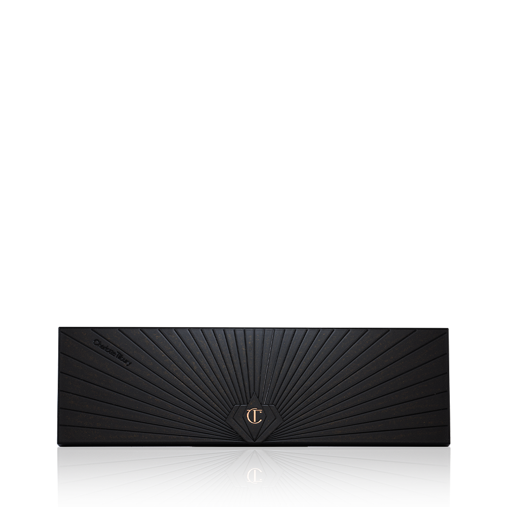 A closed, 12-pan eyeshadow palette with a black-coloured lid with a golden-coloured starburst pattern on the top.