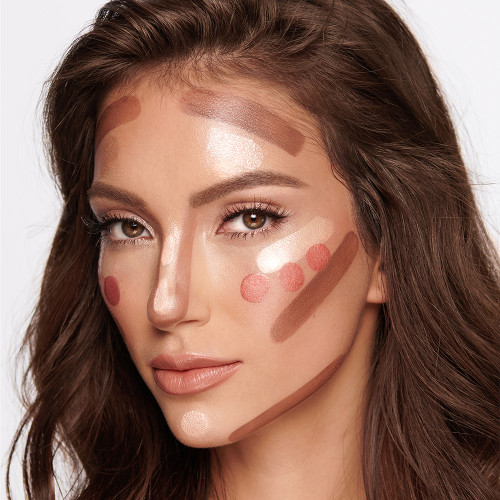 Medium-tone brunette model with unblended contour, medium-pink glowy blush, and an extremely glowy, champagne-coloured highlighter on her face. 