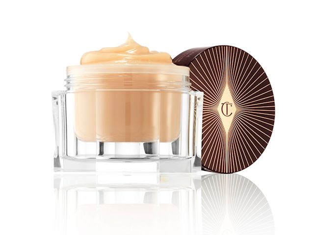 A thick butterscotch-coloured moisturiser in a big, open glass jar with its dark-crimson-coloured lid next to it. 