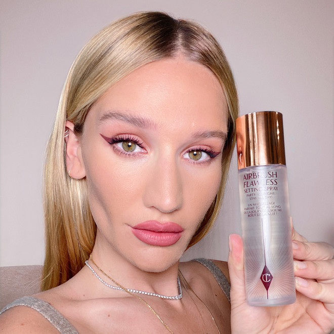 Sofia Tilbury holding a setting spray in a clear bottle with a gold-coloured lid.