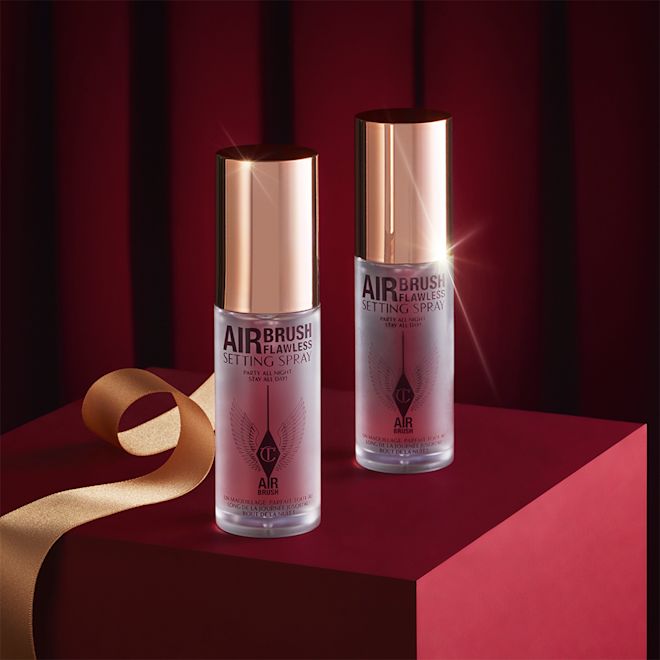 Airbrush Flawless Setting Spray Duo travel-size closed Two, identical mini, setting sprays in clear bottles with gold-coloured lids.