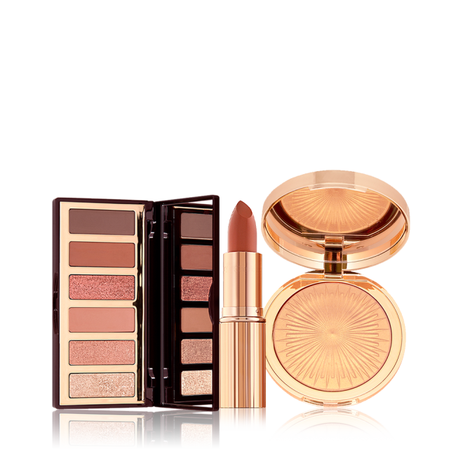 An open, 6-pan eyeshadow palette with a mirrored lid and matte and shimmery eyeshadows in shades of pink, pink, and brown, an open lipstick in a nude brick rose shade, and a highlighter compact in a soft gold shade.