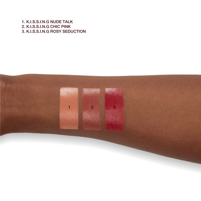Deep skin model arm close-up showing the swatches of three satin finish lipsticks in shades of nude peach, medium pink, and deep rose pink.