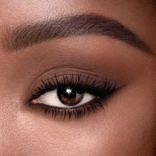Single-eye close-up of a deep-tone model with brown eyes wearing a soft chocolate brown cream eyeshadow with a matte finish.