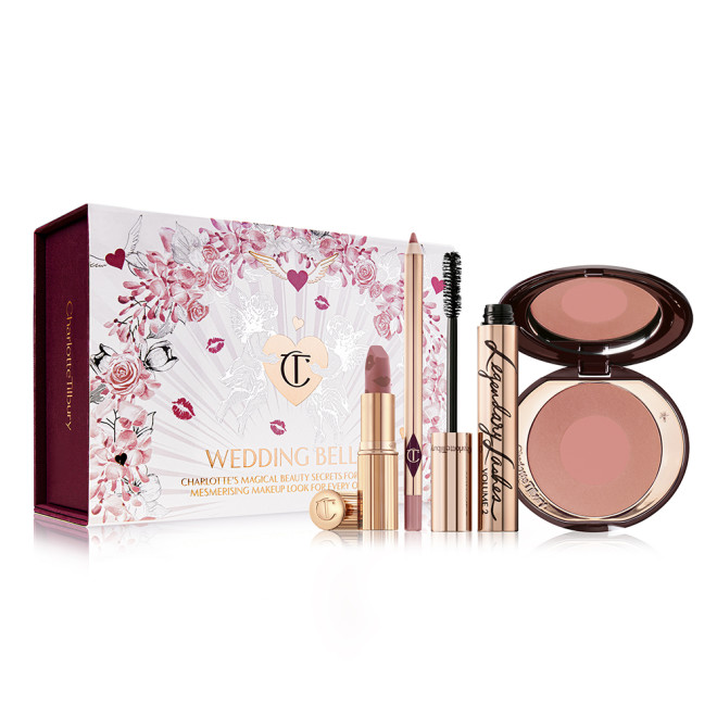 An open lipstick with a nude pink lip liner pencil, an open mascara in golden-coloured packaging, and an open two-tone blush in terracotta and warm pink with a white-coloured gift box with hearts and lipstick kiss prints all over with the text, 'Wedding Belles' written on the front. 