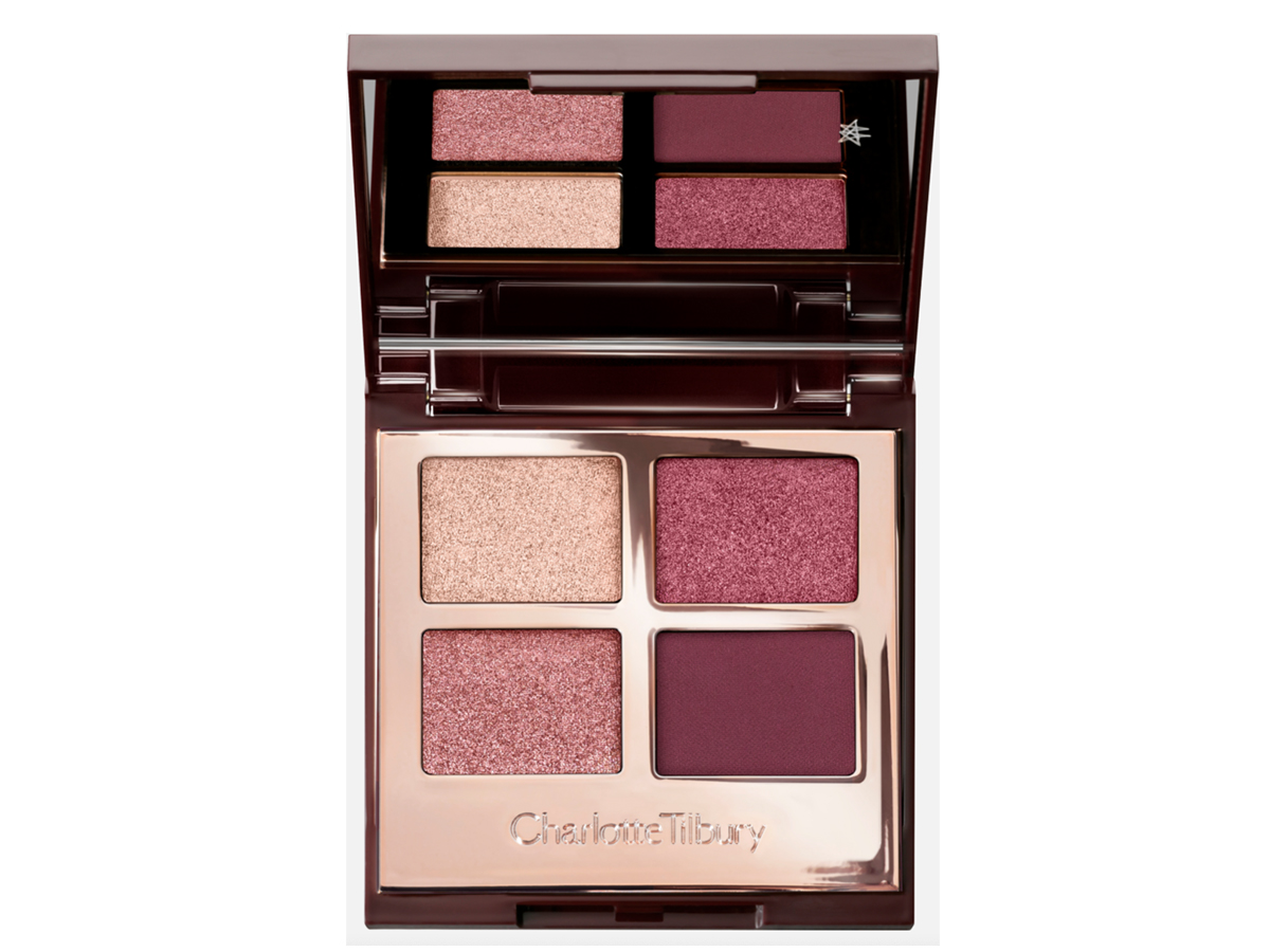 An open, mirrored-lid eyeshadow palette in matte and shimmery purple, pink, and beige shades.