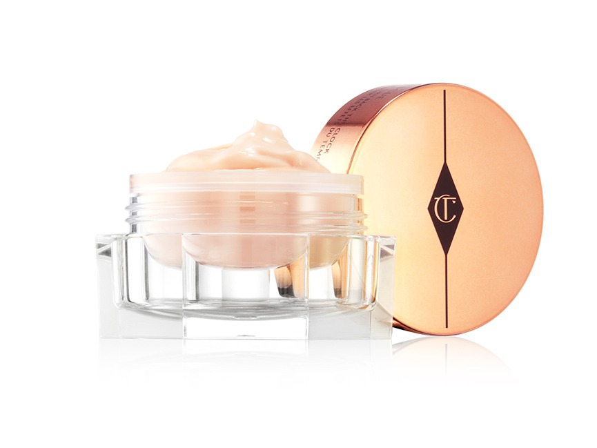 A thick, champagne-coloured eye cream in an open, petite glass jar with its golden-coloured metallic lid next to it. 