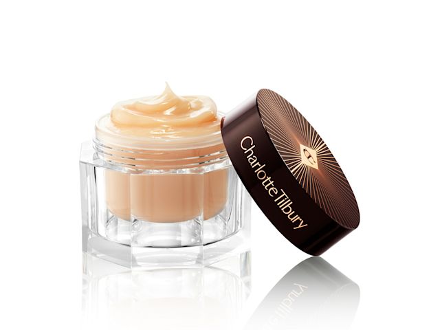 A thick and luscious dark champagne-coloured face cream in an open glass jar with a black and gold coloured lid. 
